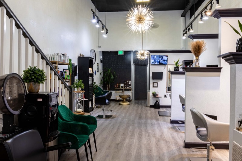The salon floor from the wash area: dryer chair, green velvet seats and starburst chandeliers